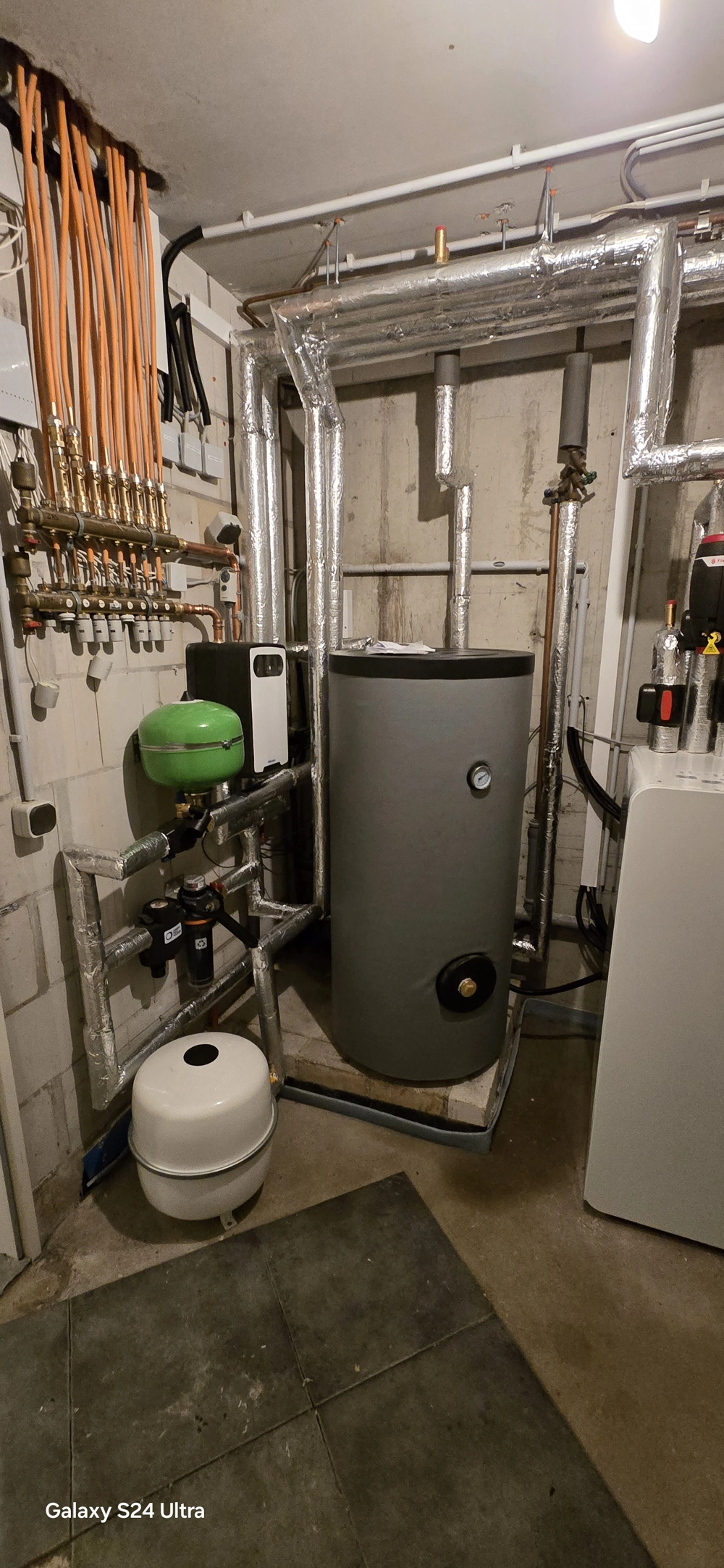 Zaizolowany zbiornik buforowy z rurami i rozdzielaczem w kotłowni – Pompy ciepła powietrze woda