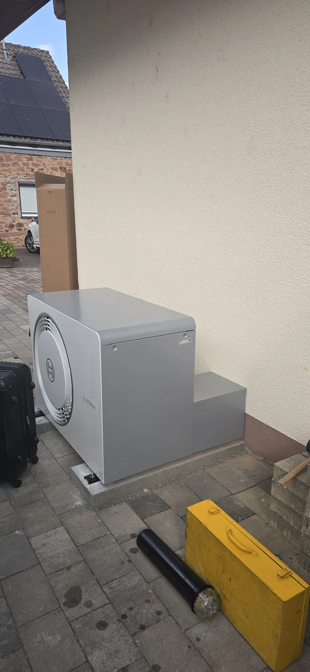 Montaż pompy ciepła – zewnętrzna jednostka powietrznej pompy ciepła przy ścianie budynku na przygotowanym podłożu