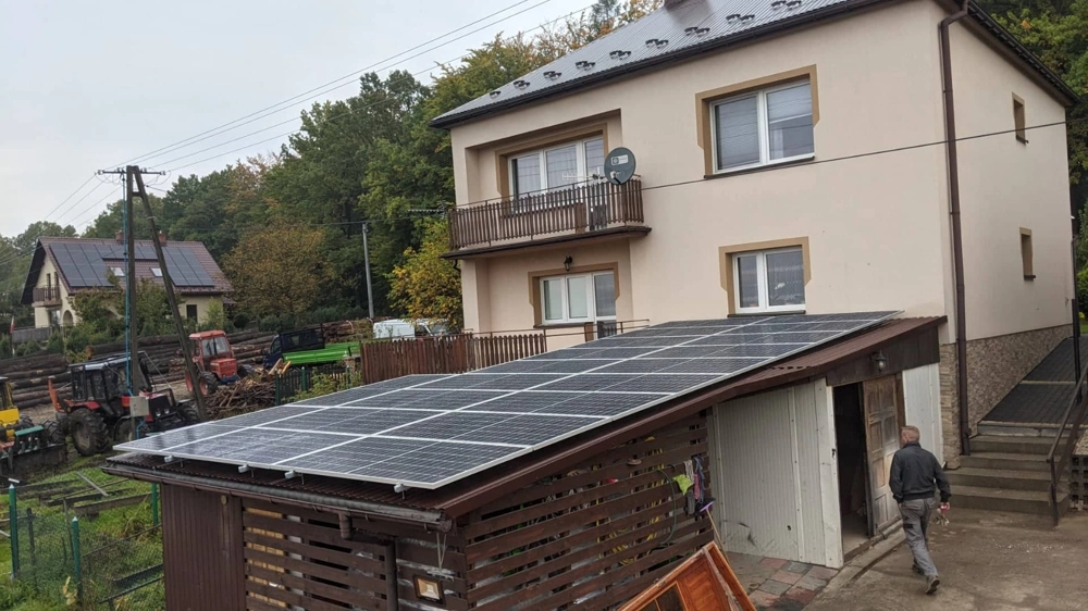 Panele fotowoltaiczne zamontowane na dachu wiaty garażowej przy domu jednorodzinnym