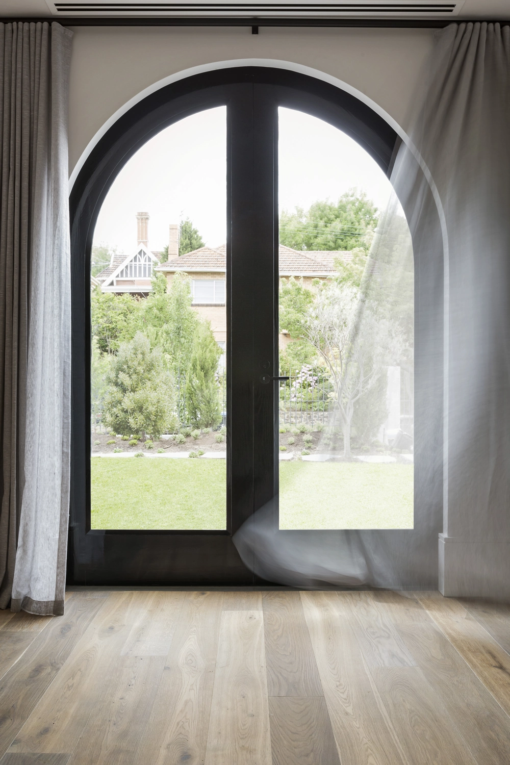 Nowoczesne łukowate drzwi tarasowe z czarną ramą i zwiewną zasłoną Montaż drzwi